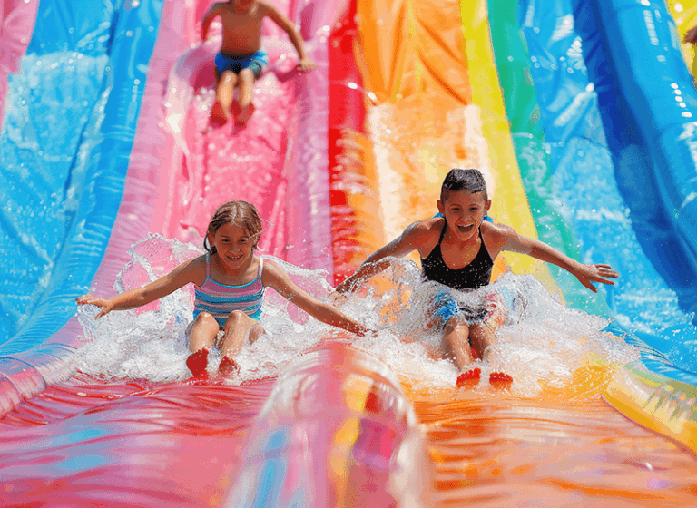 two-children-sliding-down-water-slide-amusement-park.png